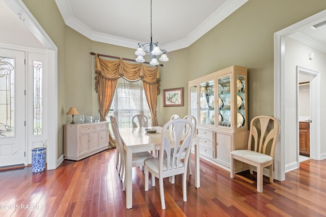 dining room featuring an inviting chandelier, wood finished floors, baseboards, and ornamental molding