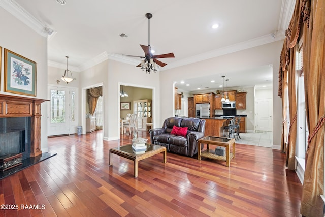 living area featuring a ceiling fan, light wood-style floors, and ornamental molding