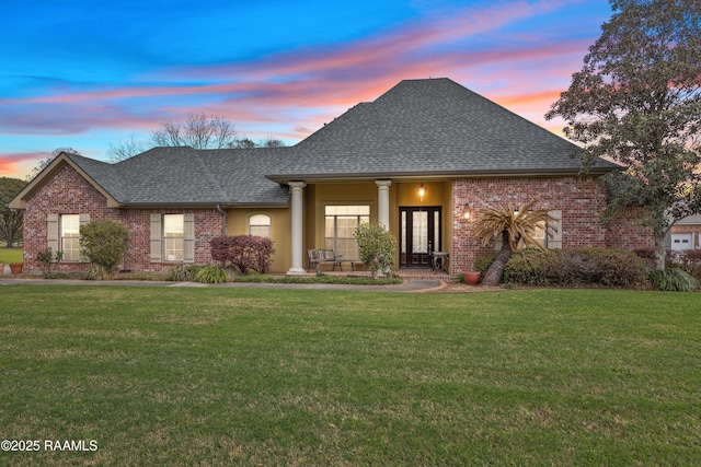 view of front of property with brick siding, a front yard, and a shingled roof