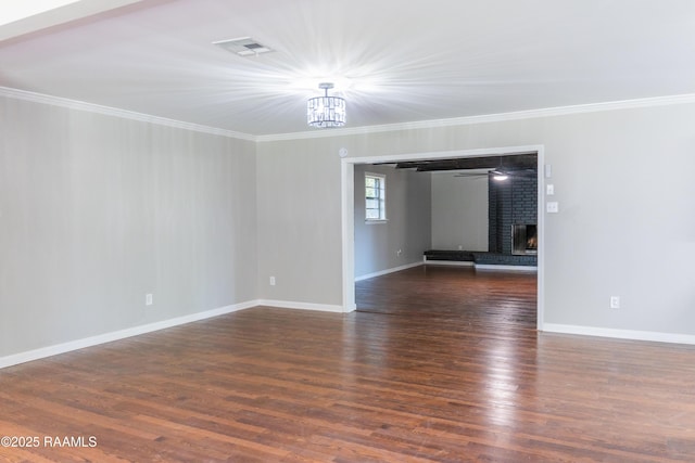 empty room with visible vents, crown molding, wood finished floors, baseboards, and a chandelier