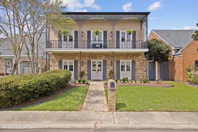 13 Heatherstone Dr, Lafayette, LA 70508 - view of front of home with stucco siding, french doors, a balcony, a front lawn, and brick siding