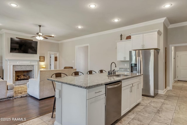 114 Marigold Ln, Maurice, LA 70555 - kitchen featuring a breakfast bar, ceiling fan, appliances with stainless steel finishes, a sink, and light stone counters