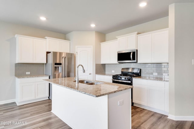 kitchen with light wood-style flooring, a sink, white cabinetry, an island with sink, and appliances with stainless steel finishes