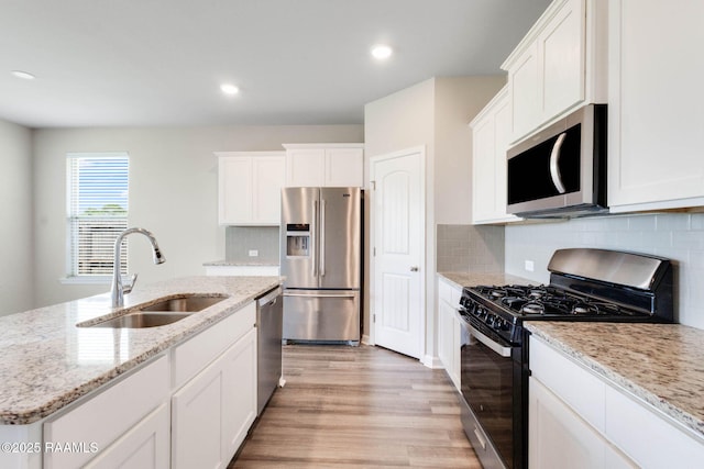 kitchen featuring light wood-type flooring, white cabinets, a sink, and appliances with stainless steel finishes