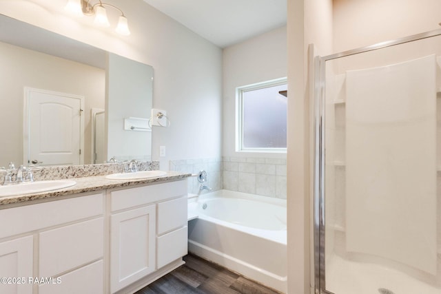 full bath with wood finished floors, a garden tub, a stall shower, and a sink