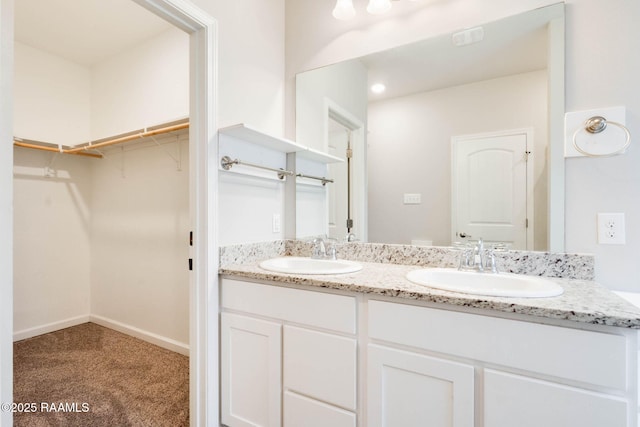 full bathroom featuring a spacious closet, a sink, and double vanity