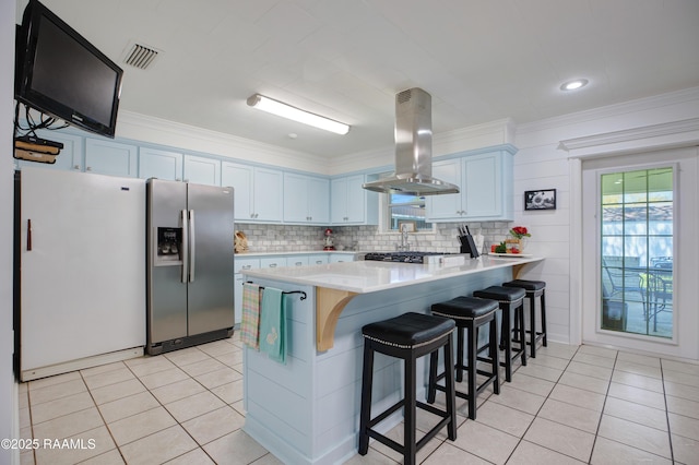 kitchen featuring freestanding refrigerator, stainless steel fridge, a peninsula, visible vents, and island range hood