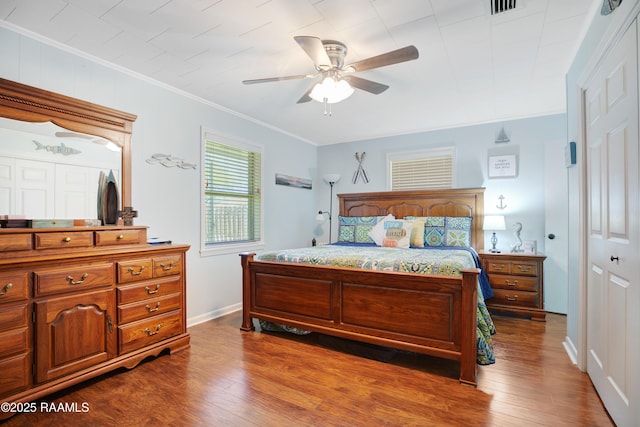 bedroom with baseboards, dark wood-style floors, a ceiling fan, and crown molding