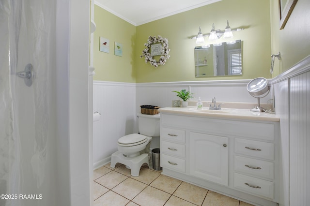 bathroom with crown molding, toilet, tile patterned floors, vanity, and wainscoting