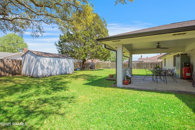 view of yard with an outdoor structure, a shed, a fenced backyard, ceiling fan, and a patio area