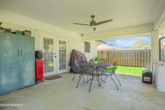 view of patio with fence, outdoor dining area, french doors, and a ceiling fan