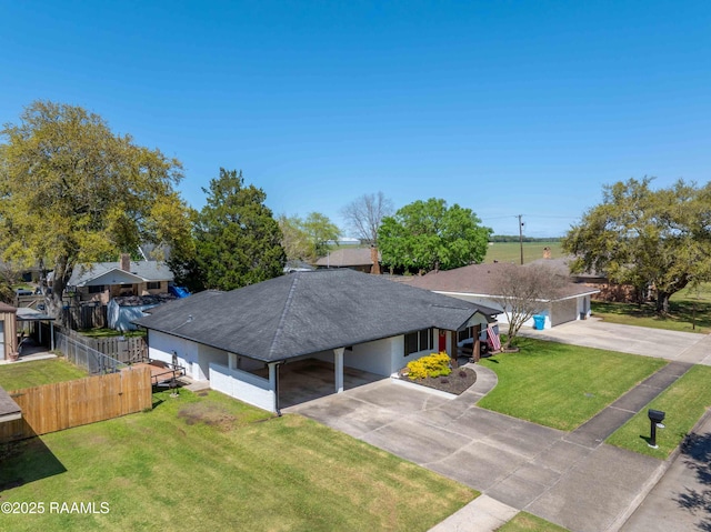 view of front of house featuring fence, an attached carport, a front lawn, driveway, and a shingled roof