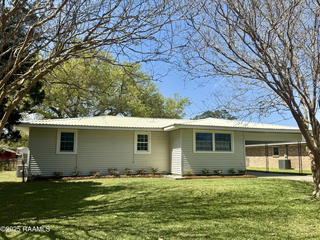 rear view of house featuring metal roof, a yard, and a carport