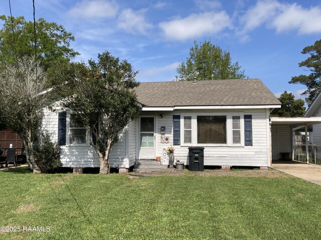 ranch-style house with an attached carport, driveway, entry steps, and a front yard