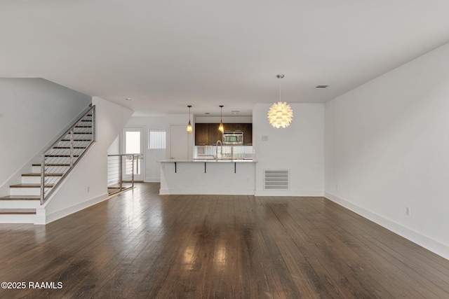 1201 S College Rd Unit 10, Lafayette, LA 70503 - unfurnished living room featuring visible vents, baseboards, dark wood-style floors, stairway, and a sink