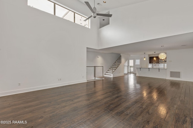 1201 S College Rd Unit 10, Lafayette, LA 70503 - unfurnished living room with visible vents, dark wood-style floors, stairway, a sink, and ceiling fan with notable chandelier