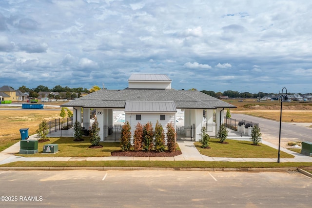 view of front facade with a fenced front yard, a front lawn, and roof with shingles