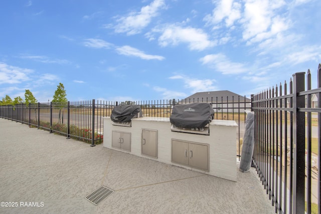 view of patio / terrace with exterior kitchen, area for grilling, and fence