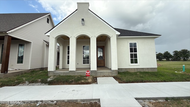 211 Keystone Dr, Scott, LA 70583 - view of exterior entry featuring a porch, stucco siding, roof with shingles, and a lawn