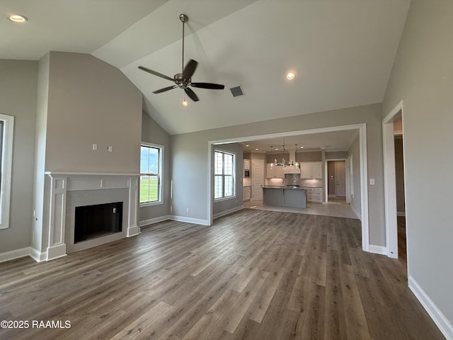 205 Keystone Dr, Scott, LA 70583 - unfurnished living room with a fireplace, ceiling fan, a chandelier, high vaulted ceiling, and wood finished floors