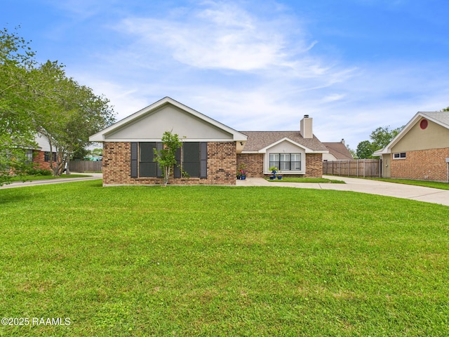 ranch-style home featuring brick siding, a chimney, fence, and a front lawn