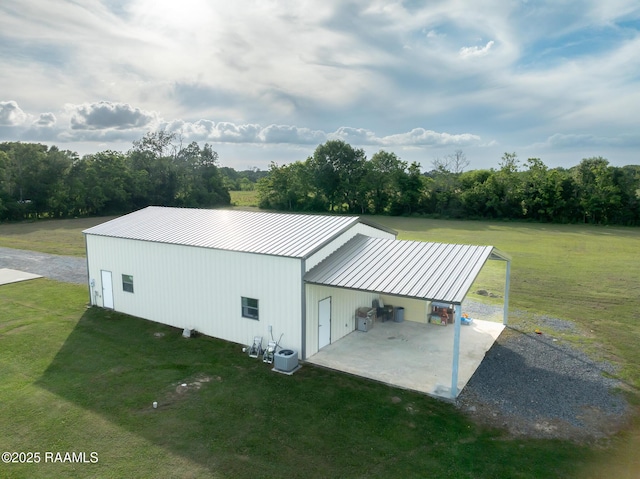 exterior space featuring a yard, an outbuilding, metal roof, and a carport