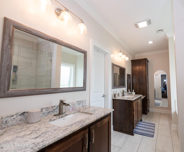 bathroom with two vanities, visible vents, ornamental molding, and a sink