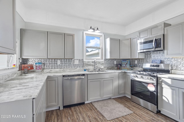kitchen featuring backsplash, gray cabinets, a sink, and appliances with stainless steel finishes