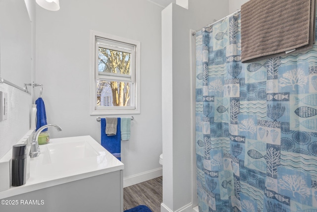 bathroom featuring baseboards, wood finished floors, toilet, vanity, and a shower with curtain