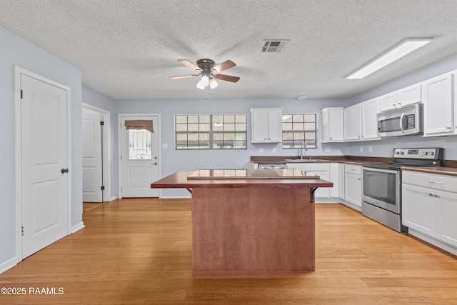 kitchen with visible vents, light wood-type flooring, a kitchen island, and stainless steel appliances