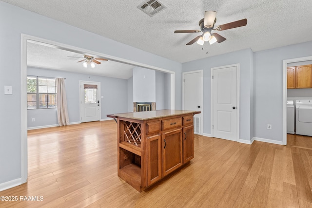 kitchen with light wood-style flooring, visible vents, ceiling fan, and washer and dryer