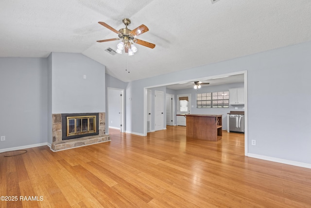 unfurnished living room featuring visible vents, ceiling fan, light wood finished floors, and a glass covered fireplace