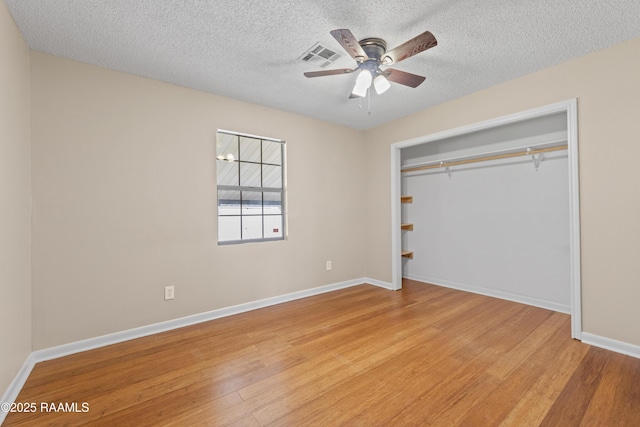 unfurnished bedroom with a closet, baseboards, light wood-type flooring, and a textured ceiling