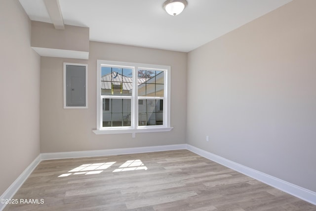 empty room featuring electric panel, baseboards, and light wood-style flooring