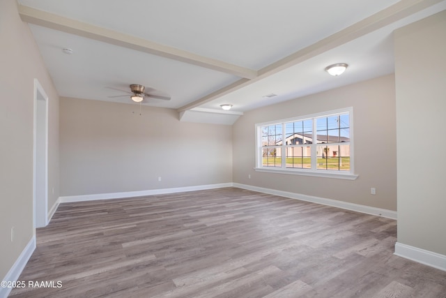 empty room featuring a ceiling fan, lofted ceiling with beams, baseboards, and wood finished floors