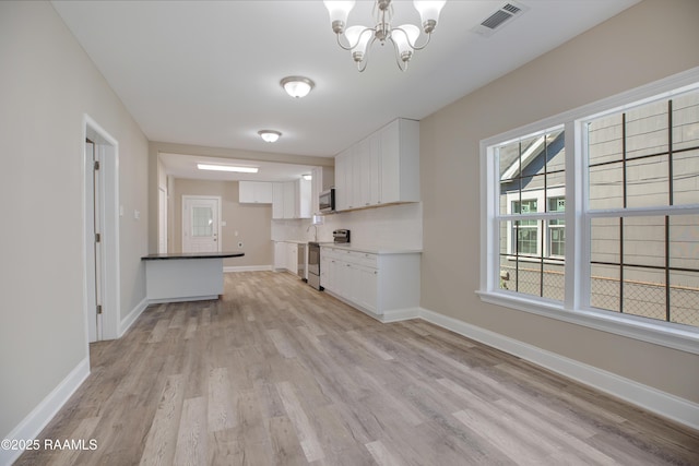 kitchen with white cabinets, visible vents, light wood finished floors, appliances with stainless steel finishes, and a notable chandelier