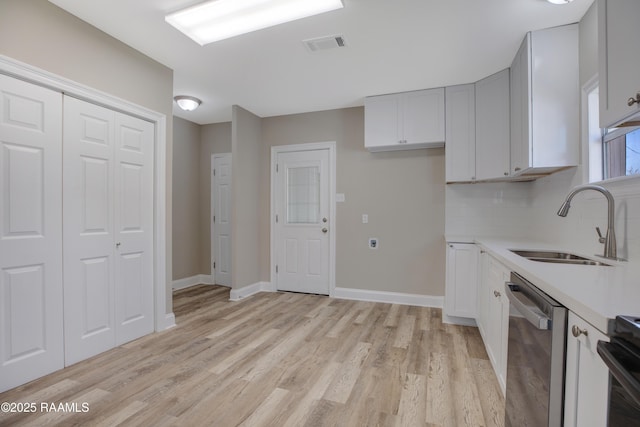 kitchen featuring light countertops, a sink, visible vents, dishwasher, and light wood-style flooring