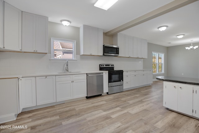 kitchen featuring a healthy amount of sunlight, light wood-type flooring, stainless steel appliances, decorative backsplash, and a sink