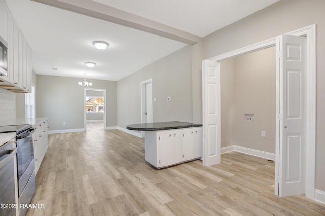 kitchen featuring a chandelier, a peninsula, light wood finished floors, appliances with stainless steel finishes, and white cabinetry