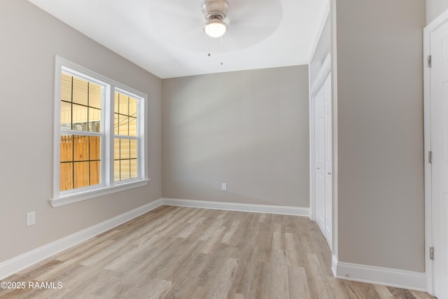 empty room with baseboards, a ceiling fan, and light wood finished floors