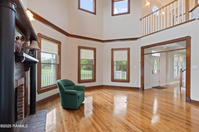 sitting room with a healthy amount of sunlight, a high ceiling, baseboards, and wood finished floors