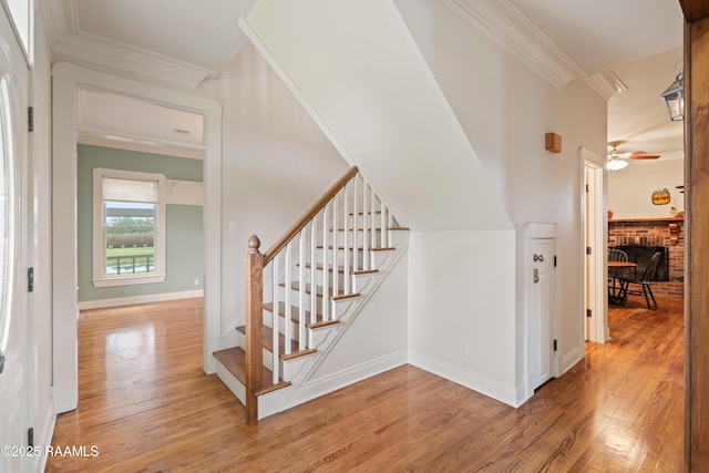 stairway featuring ceiling fan, crown molding, and wood finished floors