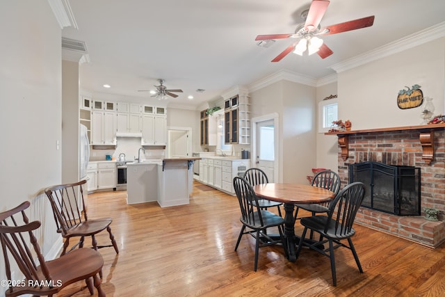 dining room with ornamental molding, light wood-type flooring, a ceiling fan, a fireplace, and recessed lighting