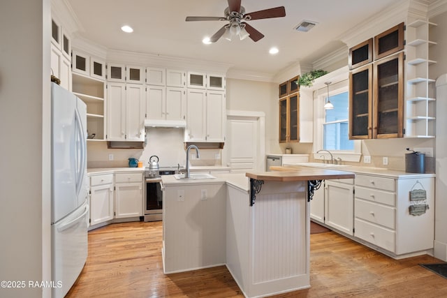 kitchen featuring freestanding refrigerator, ceiling fan, electric range, open shelves, and a kitchen island with sink