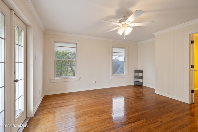 spare room with crown molding, wood finished floors, ceiling fan, and baseboards