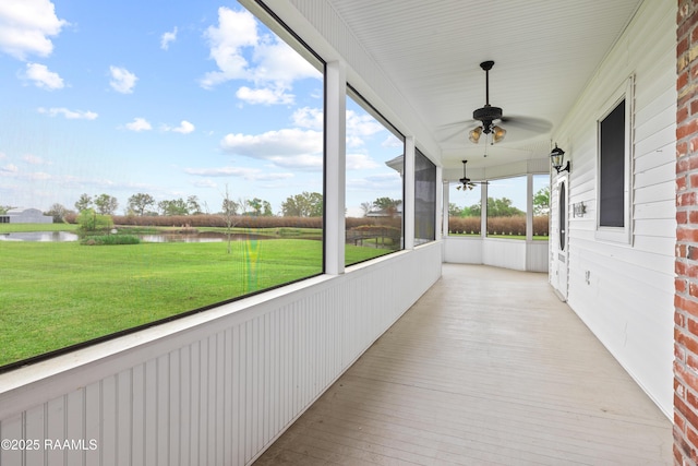 unfurnished sunroom featuring ceiling fan and a water view