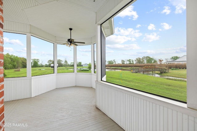 unfurnished sunroom featuring a water view and ceiling fan