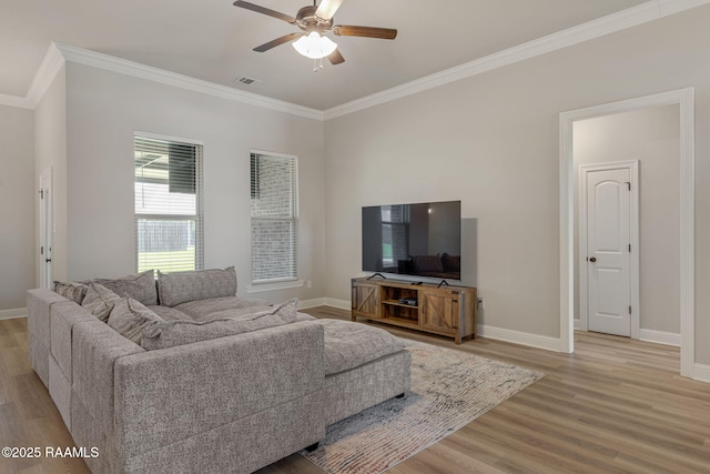 living room featuring ceiling fan, baseboards, light wood-type flooring, visible vents, and ornamental molding