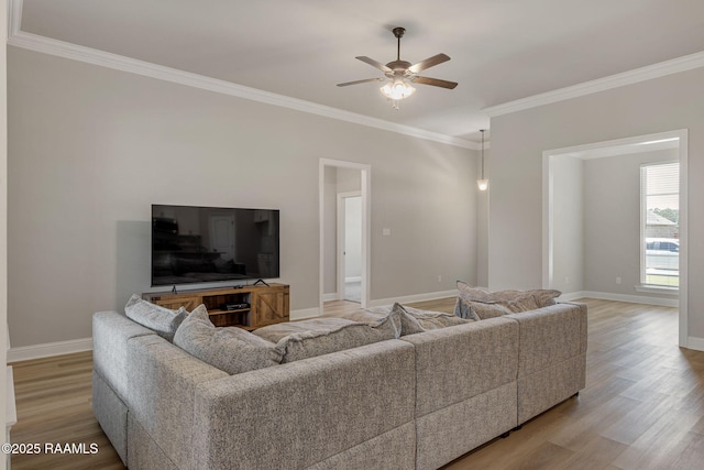 living room featuring baseboards, ceiling fan, ornamental molding, and light wood finished floors