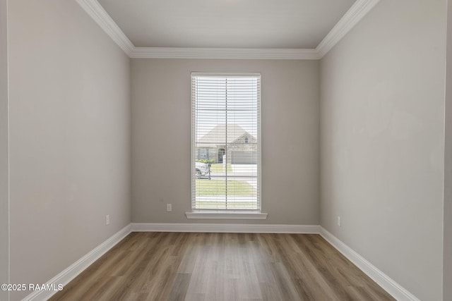spare room featuring crown molding, baseboards, and light wood-type flooring